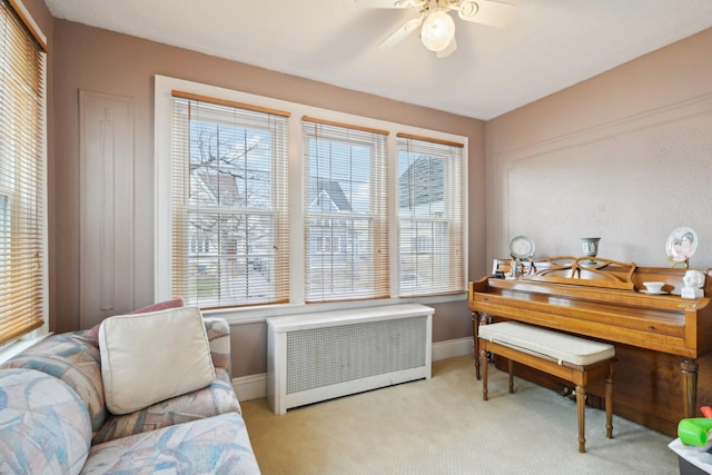 living area featuring light colored carpet, radiator, a healthy amount of sunlight, and baseboards