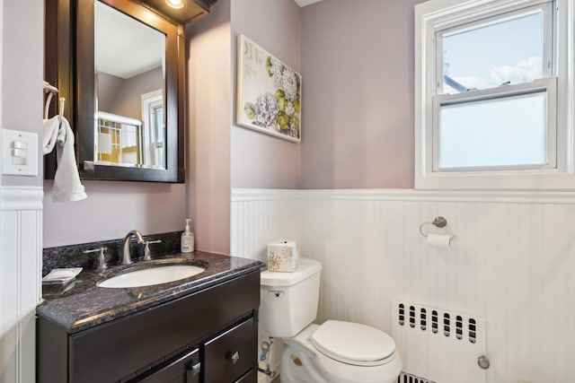 bathroom with wainscoting, vanity, toilet, and radiator