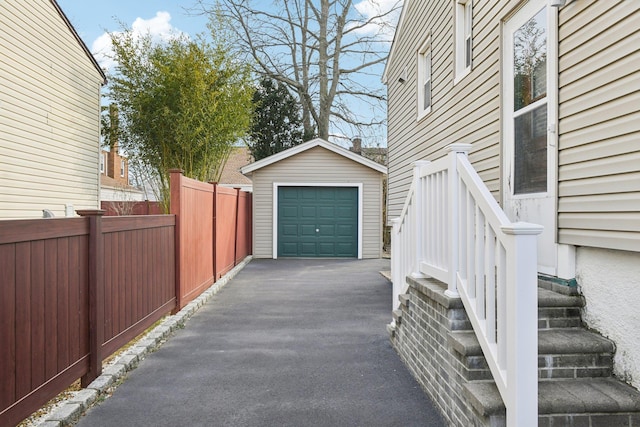 detached garage with fence and aphalt driveway