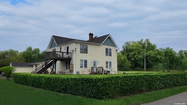 rear view of house featuring a deck and a lawn