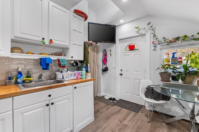 kitchen with white cabinets, butcher block counters, open shelves, and a sink