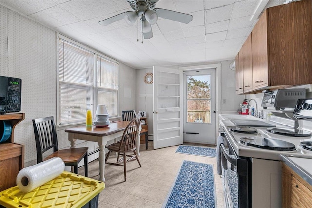 kitchen featuring ceiling fan, electric stove, light countertops, and wallpapered walls