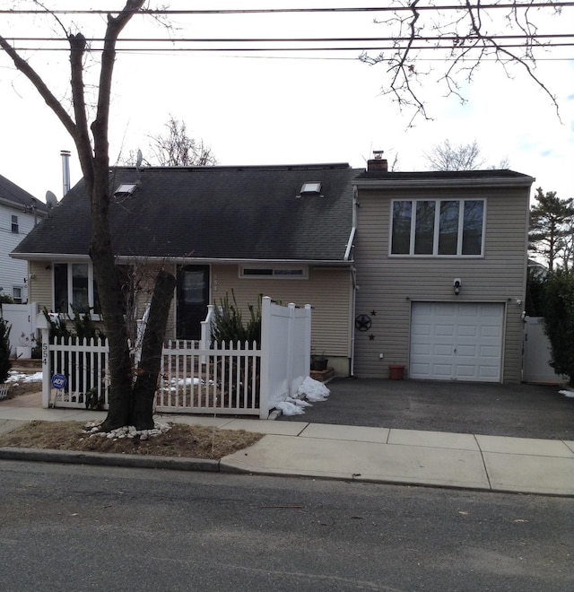 view of front of home with a garage, driveway, a chimney, and fence