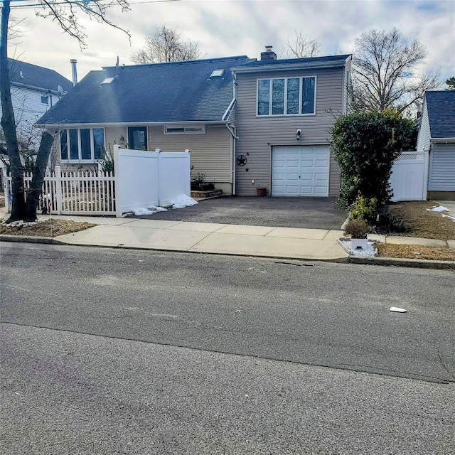 554 Grant Ave, West Hempstead, NY 11552 - traditional-style home with driveway, a chimney, a fenced front yard, and an attached garage