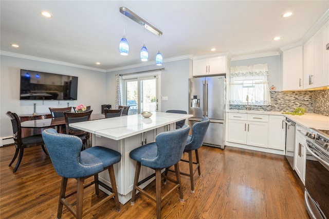 kitchen with stainless steel appliances, white cabinetry, dark wood-type flooring, and a breakfast bar area