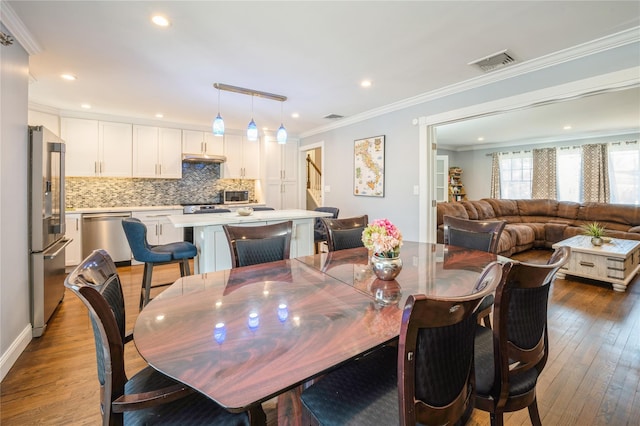 dining space featuring recessed lighting, visible vents, crown molding, and wood finished floors