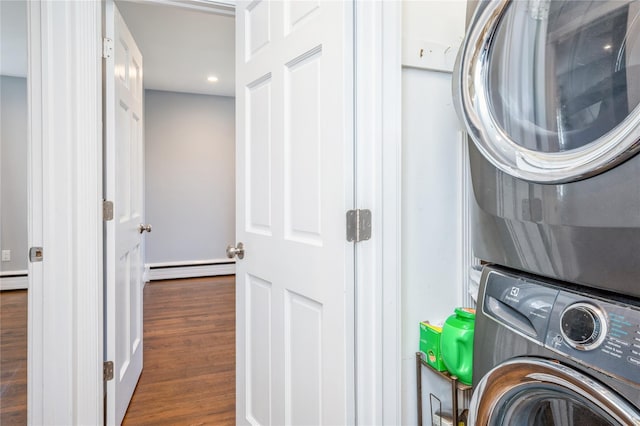 laundry room with laundry area, stacked washer / dryer, a baseboard radiator, and wood finished floors