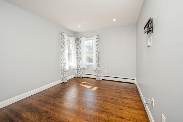 empty room featuring a baseboard heating unit, baseboards, wood finished floors, and recessed lighting