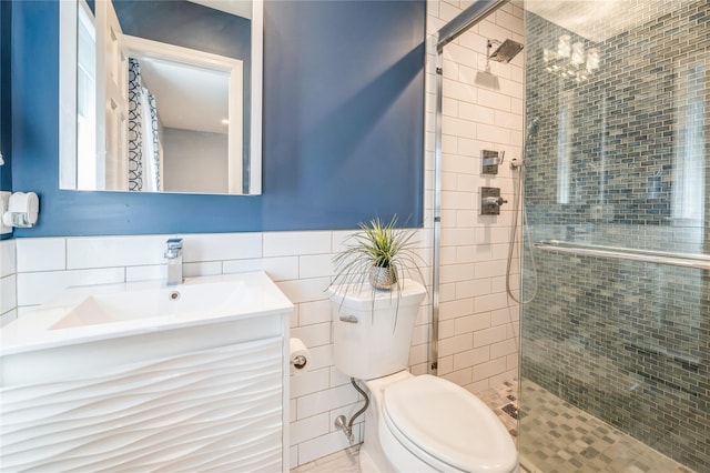 bathroom with toilet, a stall shower, vanity, and tile walls