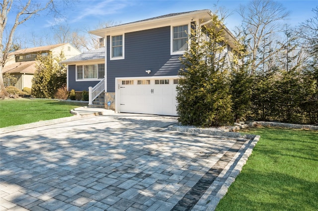 tri-level home featuring a garage, a front yard, and decorative driveway