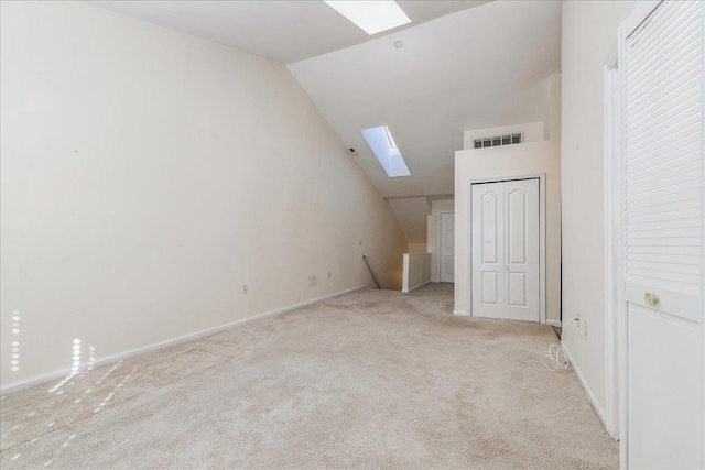 additional living space featuring light colored carpet and vaulted ceiling with skylight