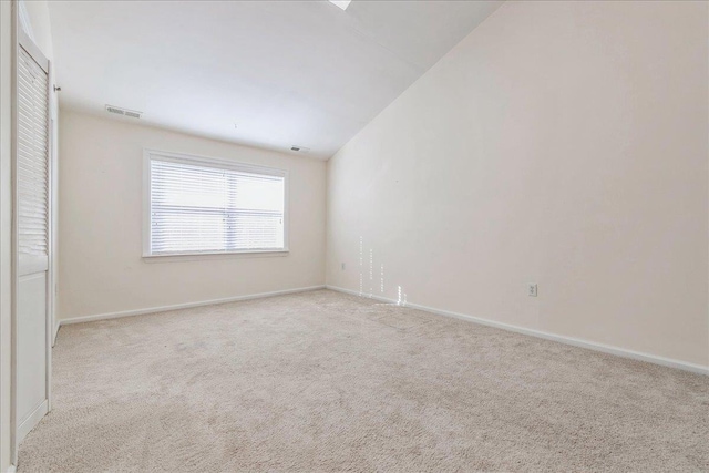 empty room with lofted ceiling and light carpet