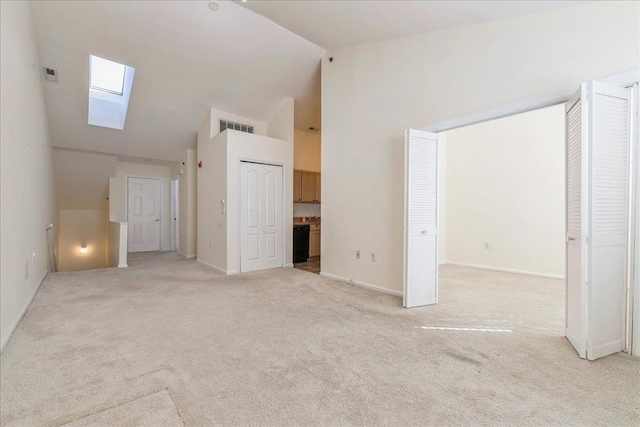 unfurnished living room with light colored carpet, a skylight, and high vaulted ceiling