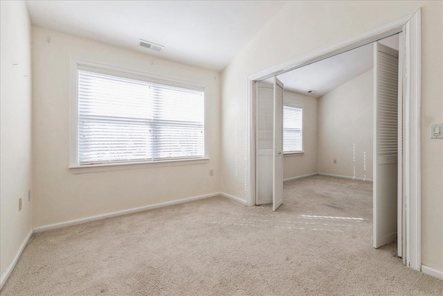 carpeted spare room featuring a healthy amount of sunlight and vaulted ceiling