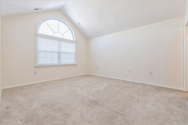 carpeted spare room with vaulted ceiling