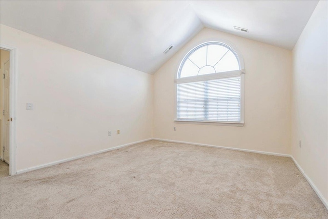 spare room featuring light carpet and vaulted ceiling