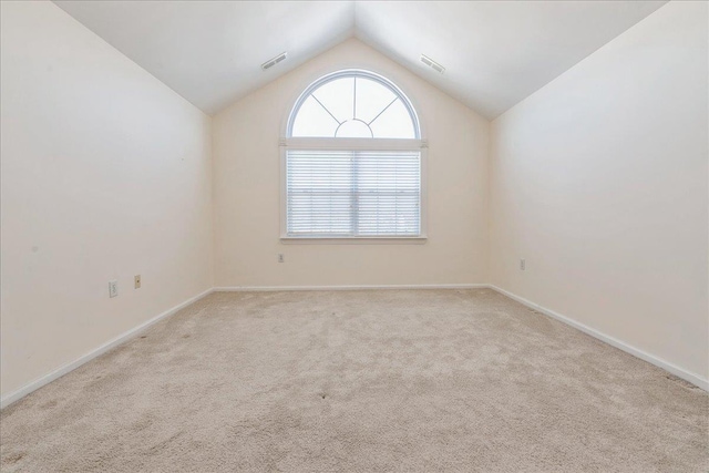 spare room featuring light carpet and lofted ceiling