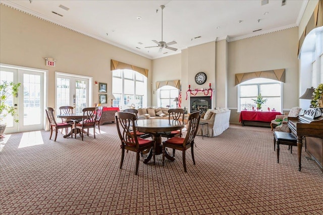 carpeted dining area featuring plenty of natural light, ornamental molding, french doors, and a high ceiling