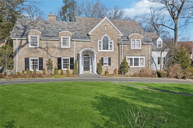 french provincial home featuring a high end roof, a front lawn, and a chimney