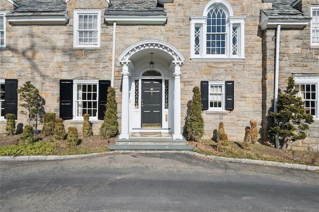 doorway to property featuring a high end roof and stone siding