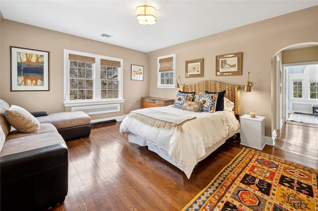 133AKA139 Hampshire Rd, Bronxville, NY 10708 - bedroom with arched walkways, dark wood-style floors, radiator heating unit, and baseboards
