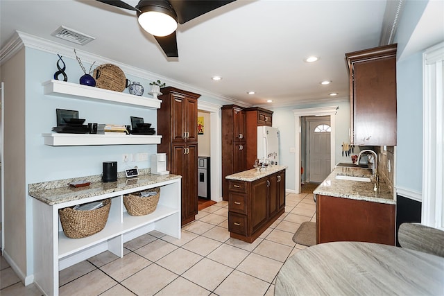 kitchen with a center island, light tile patterned floors, sink, and ornamental molding