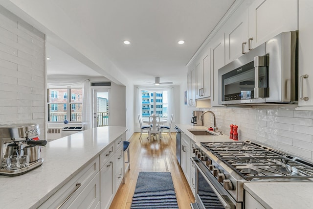 kitchen with sink, light hardwood / wood-style flooring, stainless steel appliances, tasteful backsplash, and white cabinets