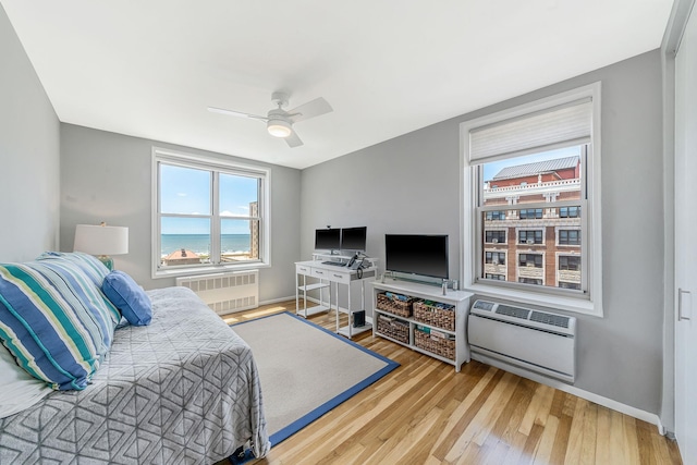 bedroom featuring hardwood / wood-style flooring, radiator, heating unit, and ceiling fan