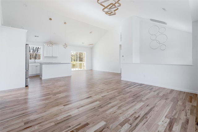 unfurnished living room featuring high vaulted ceiling and light wood-type flooring