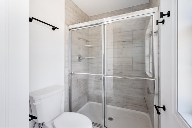 bathroom featuring toilet and a shower with shower door