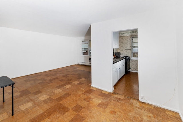 kitchen featuring black range with gas cooktop, white cabinets, dark countertops, baseboard heating, and wallpapered walls