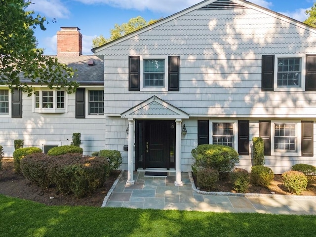 view of front of house featuring a chimney and roof with shingles