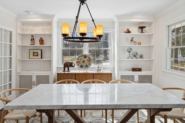 dining space with a notable chandelier, crown molding, built in features, and a wealth of natural light