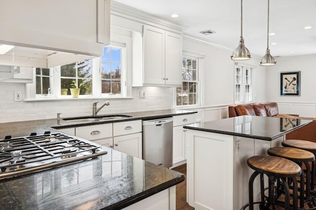 kitchen featuring appliances with stainless steel finishes, white cabinets, a kitchen island, and a kitchen bar