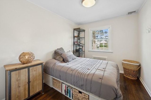 bedroom with dark wood-style flooring, visible vents, radiator heating unit, ornamental molding, and baseboards