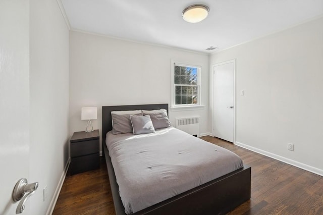 bedroom featuring baseboards, dark wood finished floors, visible vents, and radiator heating unit