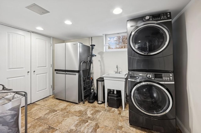 laundry room with laundry area, stacked washer and clothes dryer, and recessed lighting