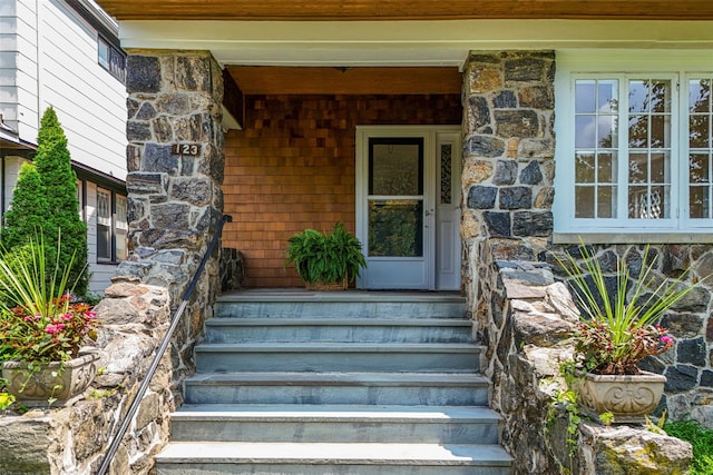 entrance to property with a porch and stone siding