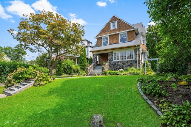 shingle-style home featuring stone siding and a front yard