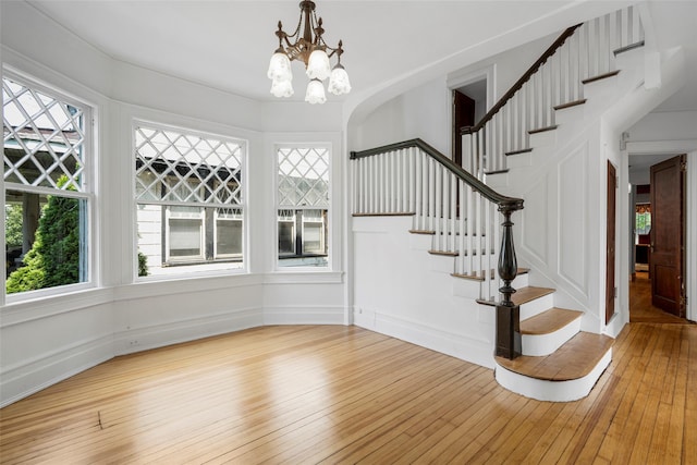 entrance foyer featuring light wood-style floors, a notable chandelier, and stairway