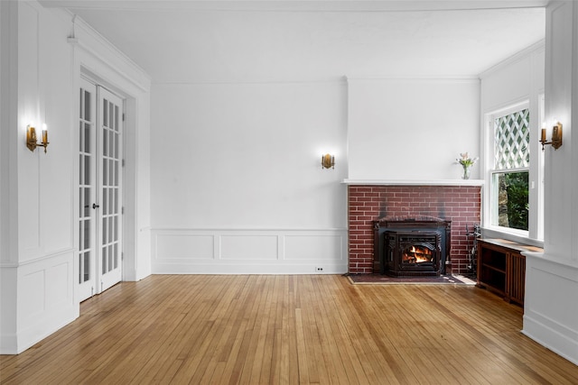 unfurnished living room with wood-type flooring, a fireplace, a decorative wall, and crown molding