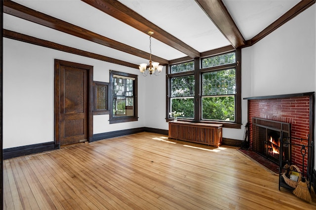 unfurnished living room with baseboards, light wood finished floors, a brick fireplace, and radiator