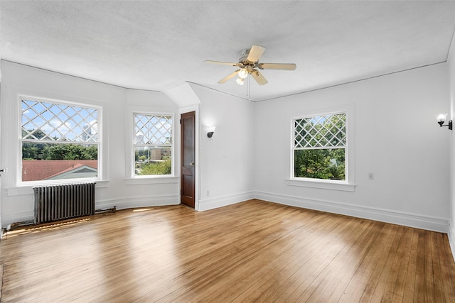 spare room featuring plenty of natural light, radiator heating unit, a textured ceiling, and hardwood / wood-style floors