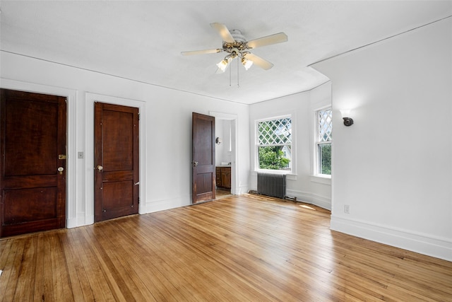 unfurnished bedroom with radiator, wood-type flooring, baseboards, and ensuite bathroom