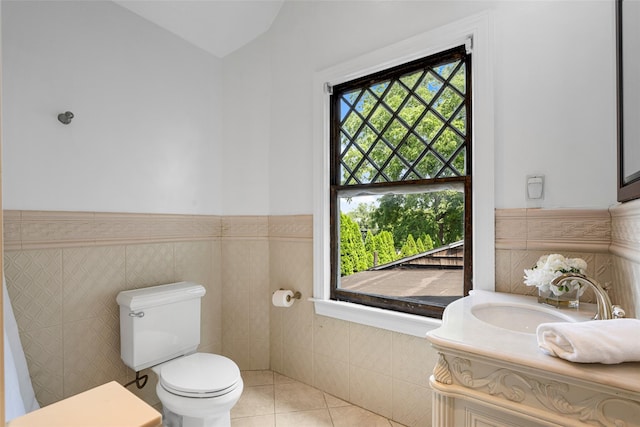 bathroom with tile patterned flooring, toilet, a wainscoted wall, vanity, and tile walls