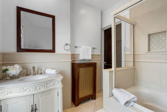 bathroom with tile walls, tile patterned floors, wainscoting, vanity, and a bath