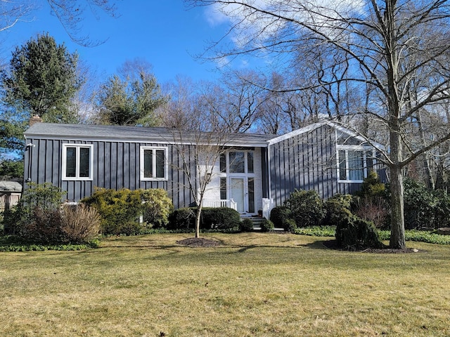 view of front of home with a chimney, board and batten siding, and a front yard