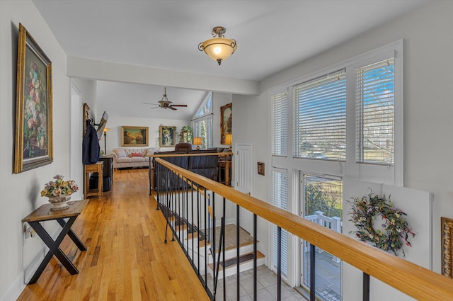 hallway with an upstairs landing, light wood-style flooring, lofted ceiling, and a wealth of natural light