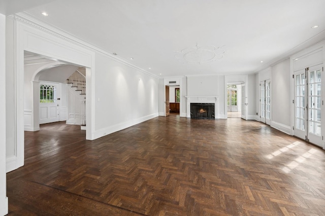 unfurnished living room featuring plenty of natural light, ornamental molding, and dark parquet floors