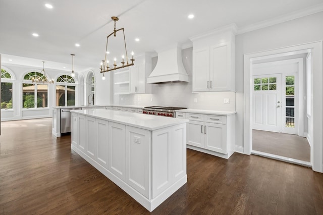 kitchen with decorative light fixtures, range, custom exhaust hood, and white cabinets